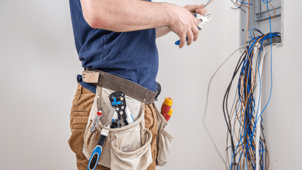 electrician builder at work, examines the cable connection in the electrical line